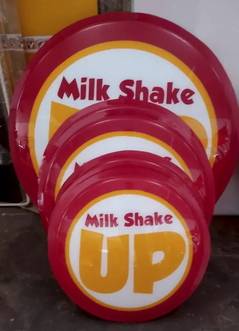Três luminosos redondos do Milk Shake Up, em vermelho e amarelo