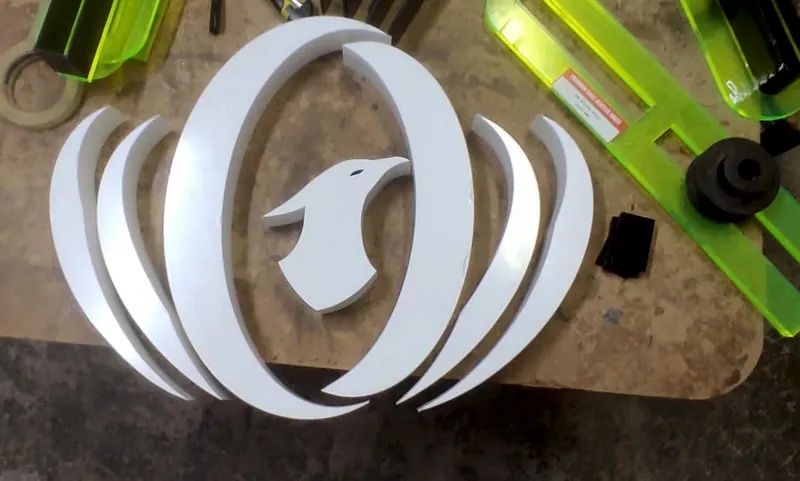 Emblema branco de ave com arcos, em acrílico, na bancada