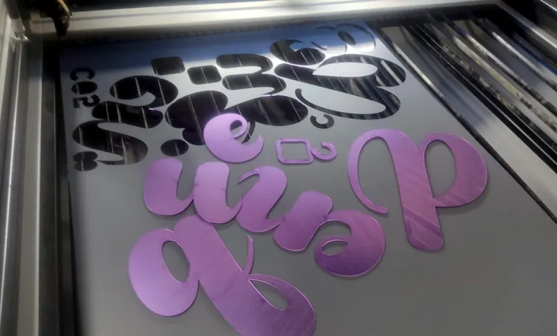 Letras roxas cortadas a laser dentro da máquina